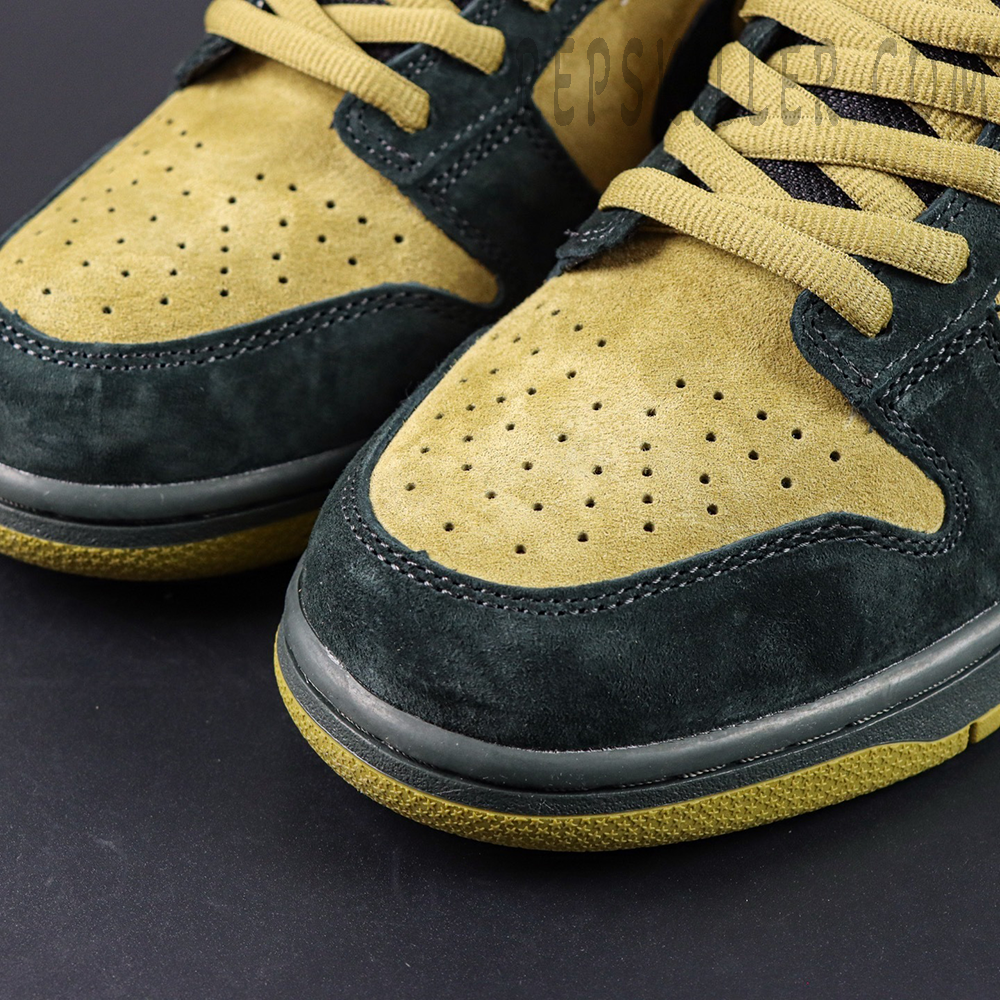 Nike Supreme x Dunk Low SB “Camper Green” toe box close-up highlighting dual-tone suede in moss green and tan with perforation details.