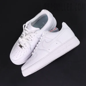 Overhead pair of NOCTA x Nike Air Force 1 Low “Certified Lover Boy” showing premium white tumbled leather and engraved midsole text.
