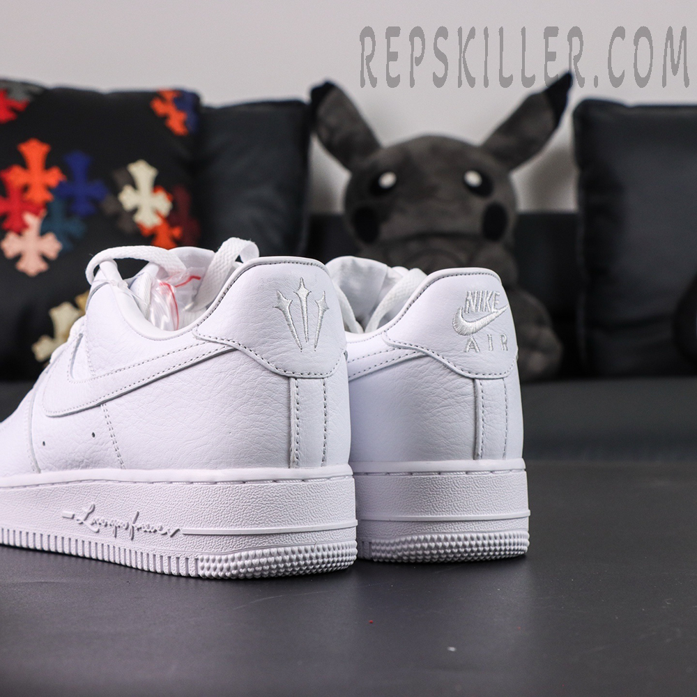 Angled rear view of NOCTA x Nike Air Force 1 “Certified Lover Boy” showing white leather construction and dual heel logos.