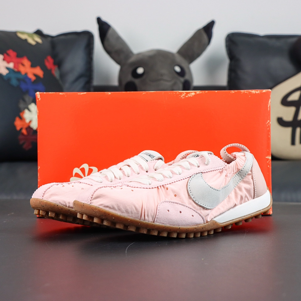 Jacquemus x Nike Moon Shoe SP “Aluminum Pink” displayed with a soft pink ruched nylon upper, metallic silver Swoosh, and vintage orange Nike shoe box