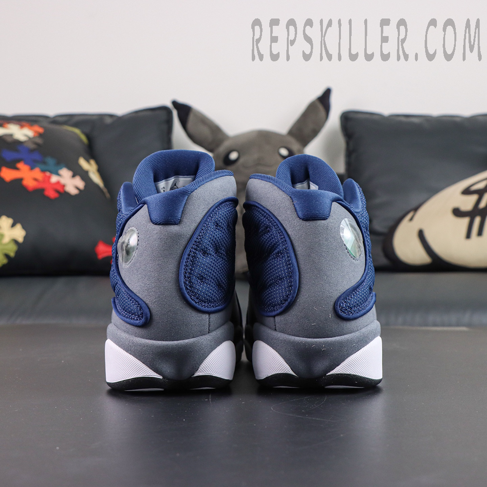 Air Jordan 13 Retro “Flint” rear heel view featuring navy mesh overlays, grey suede panels, and holographic cat eye detailing