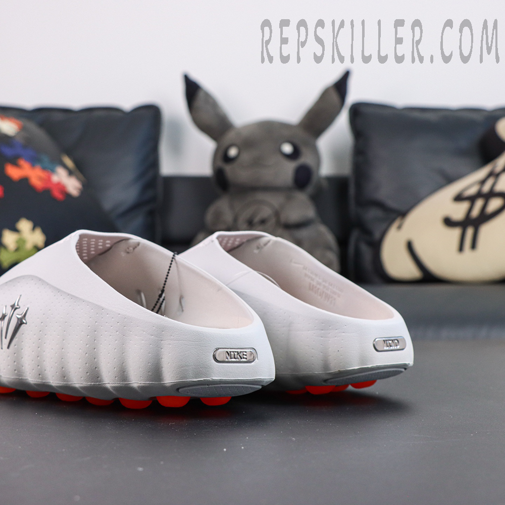 Drake NOCTA x Nike Mind 001 ‘Light Grey’ rear view featuring metallic Nike and MIND heel badges on a clean light grey silhouette