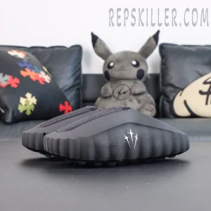 Drake NOCTA x Nike Mind 001 ‘Black’ front angled view featuring a black upper, raised NOCTA trident logo, and blue cushioning pods for a futuristic minimalist look