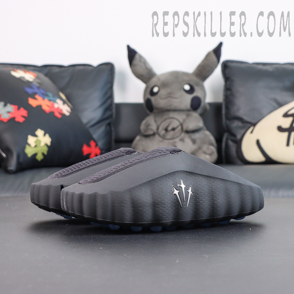 Drake NOCTA x Nike Mind 001 ‘Black’ front angled view featuring a black upper, raised NOCTA trident logo, and blue cushioning pods for a futuristic minimalist look